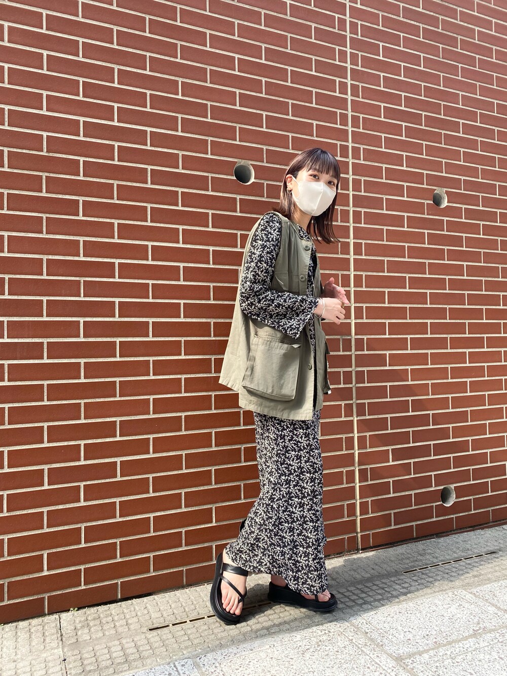 ブラック系のワンピース、グリーン系のベストを着用したレディースの春コーディネートの2枚目の写真