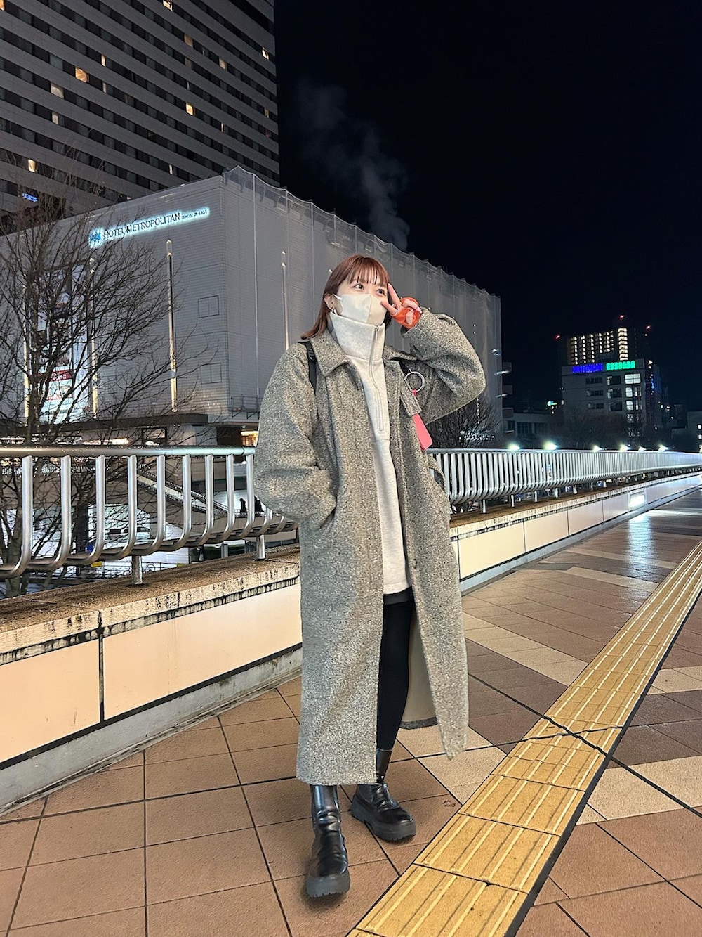 ブラウン系のステンカラーコート、ホワイト系のニット/セーターを着用したレディースの冬コーディネートの2枚目の写真