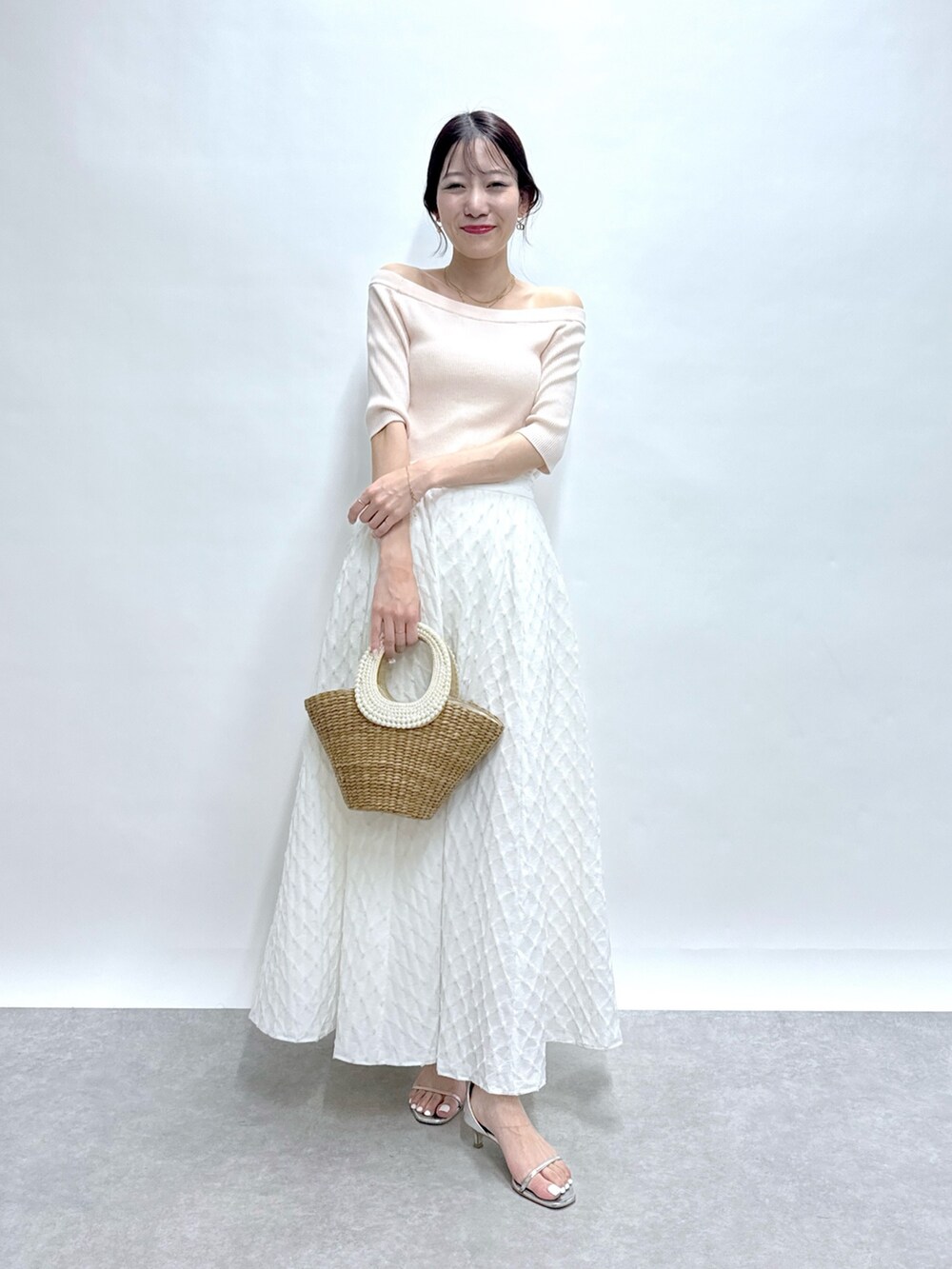 ピンク系のニット/セーター、ホワイト系のスカート、ベージュ系のかごバッグを着用したレディースの春コーディネートの5枚目の写真