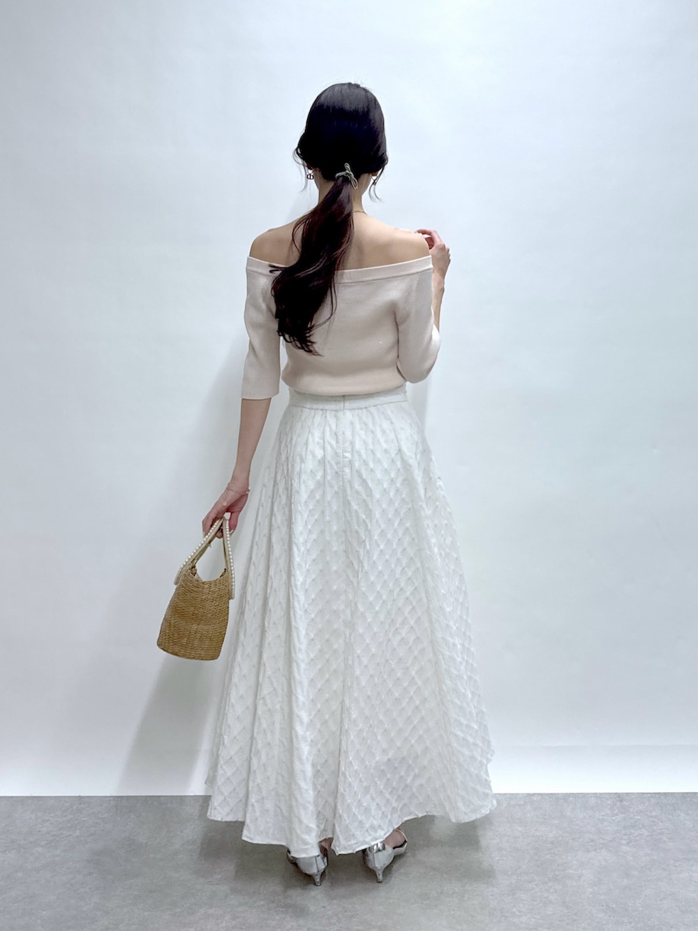 ピンク系のニット/セーター、ホワイト系のスカート、ベージュ系のかごバッグを着用したレディースの春コーディネートの4枚目の写真