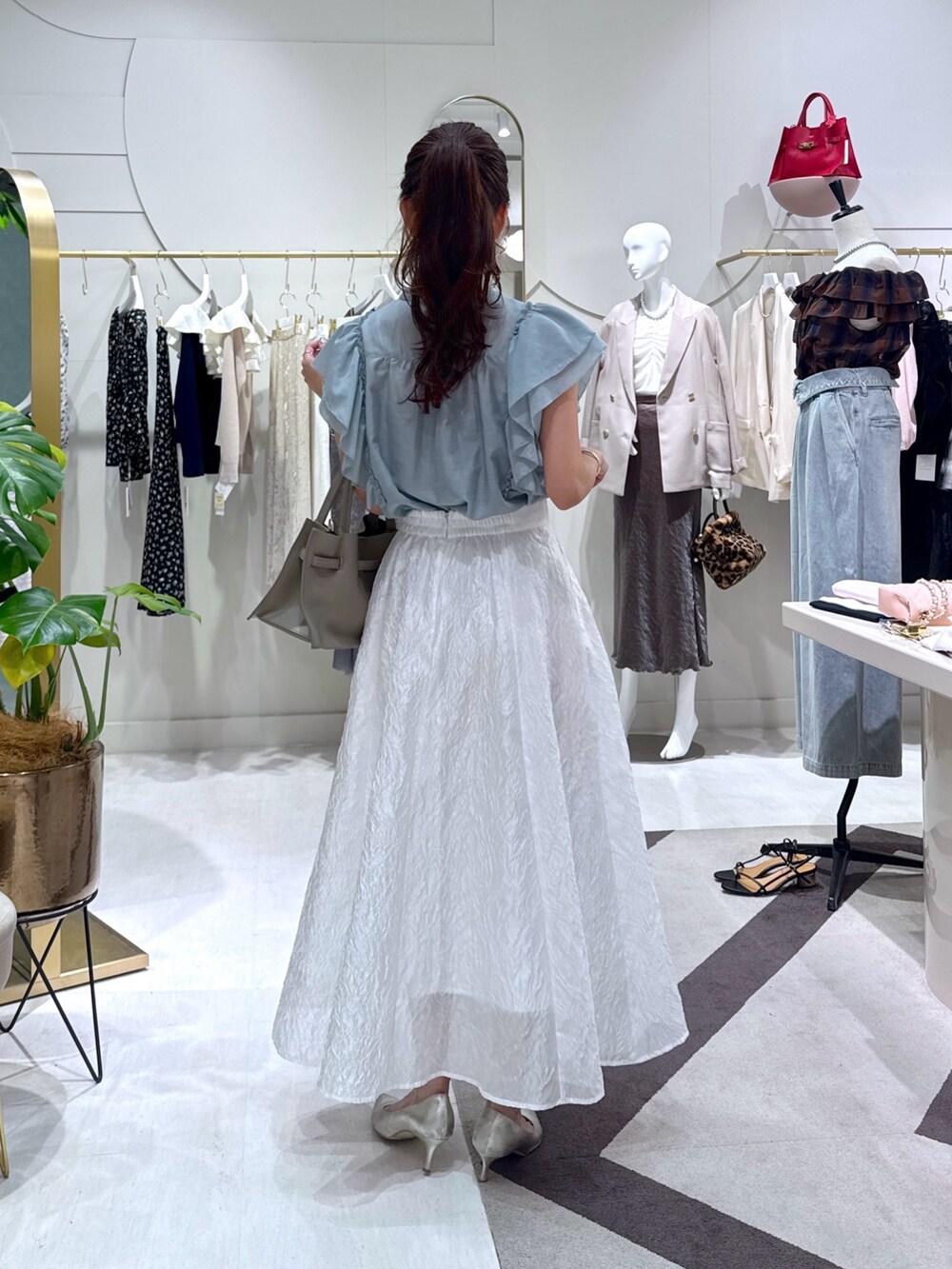 グレー系のトートバッグ、グリーン系のシャツ/ブラウス、ホワイト系のスカートを着用したレディースの秋コーディネートの4枚目の写真