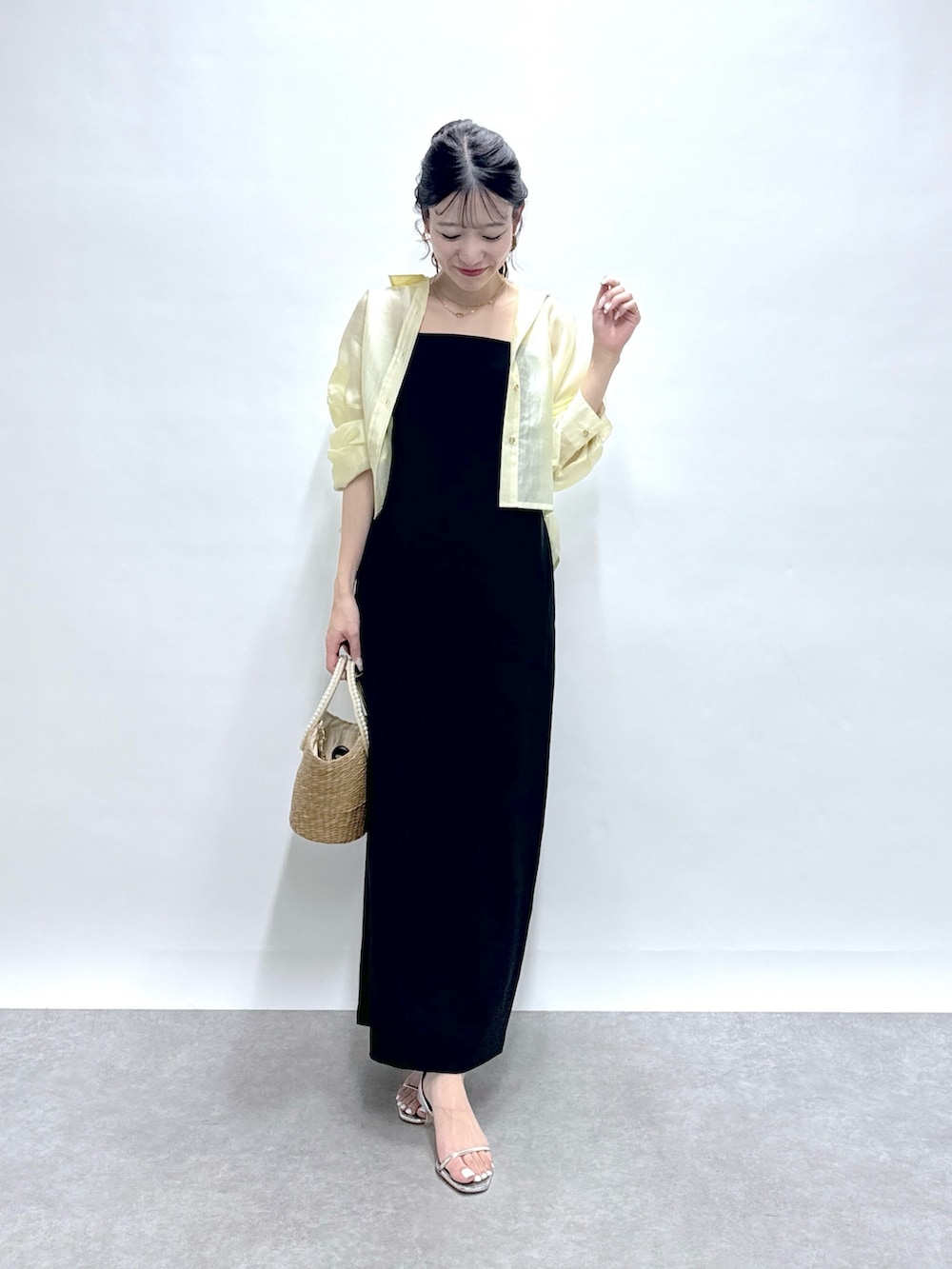 イエロー系のシャツ/ブラウス、ブラック系のワンピース、ベージュ系のかごバッグを着用したレディースの春コーディネートの5枚目の写真
