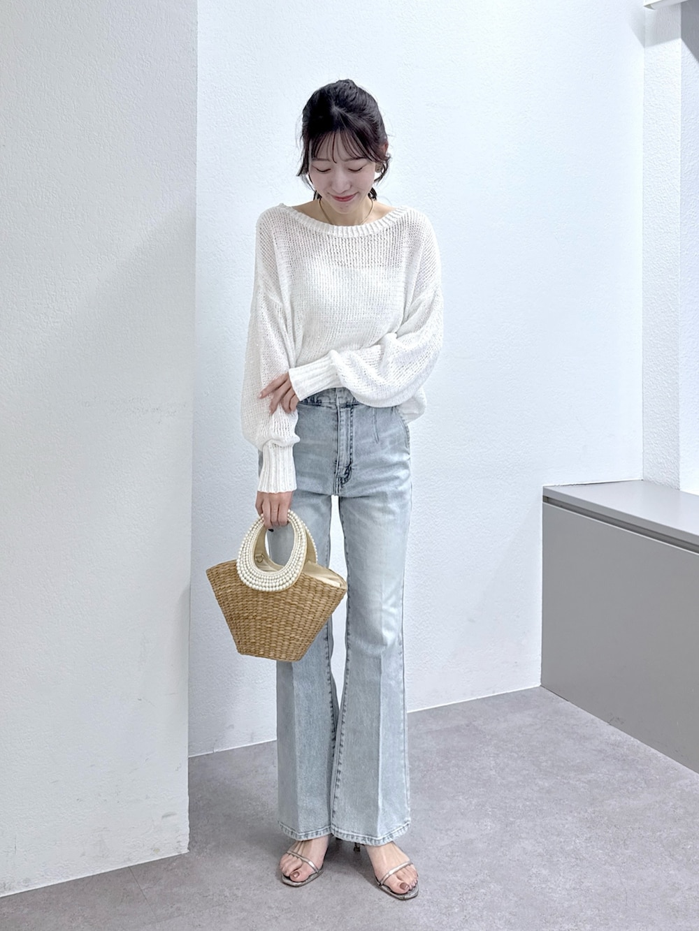 ホワイト系のニット/セーター、ブルー系のデニムパンツ、ベージュ系のかごバッグを着用したレディースの春コーディネートの2枚目の写真