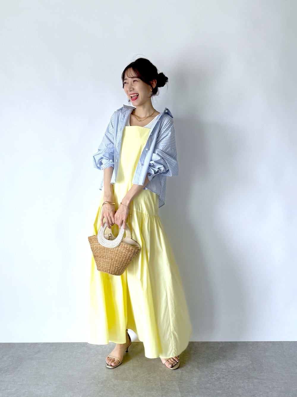 イエロー系のワンピース、ブルー系のシャツ/ブラウス、ホワイト系のタンクトップを着用したレディースの夏コーディネートの2枚目の写真