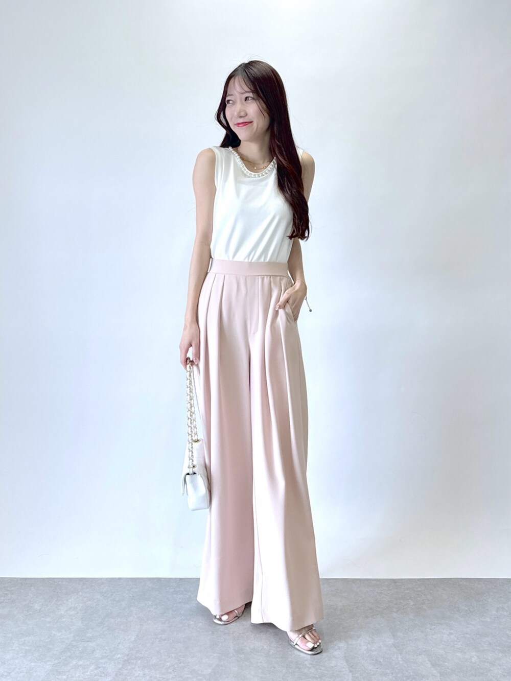 ピンク系のスラックス、ホワイト系のタンクトップを着用したレディースの春コーディネートの5枚目の写真