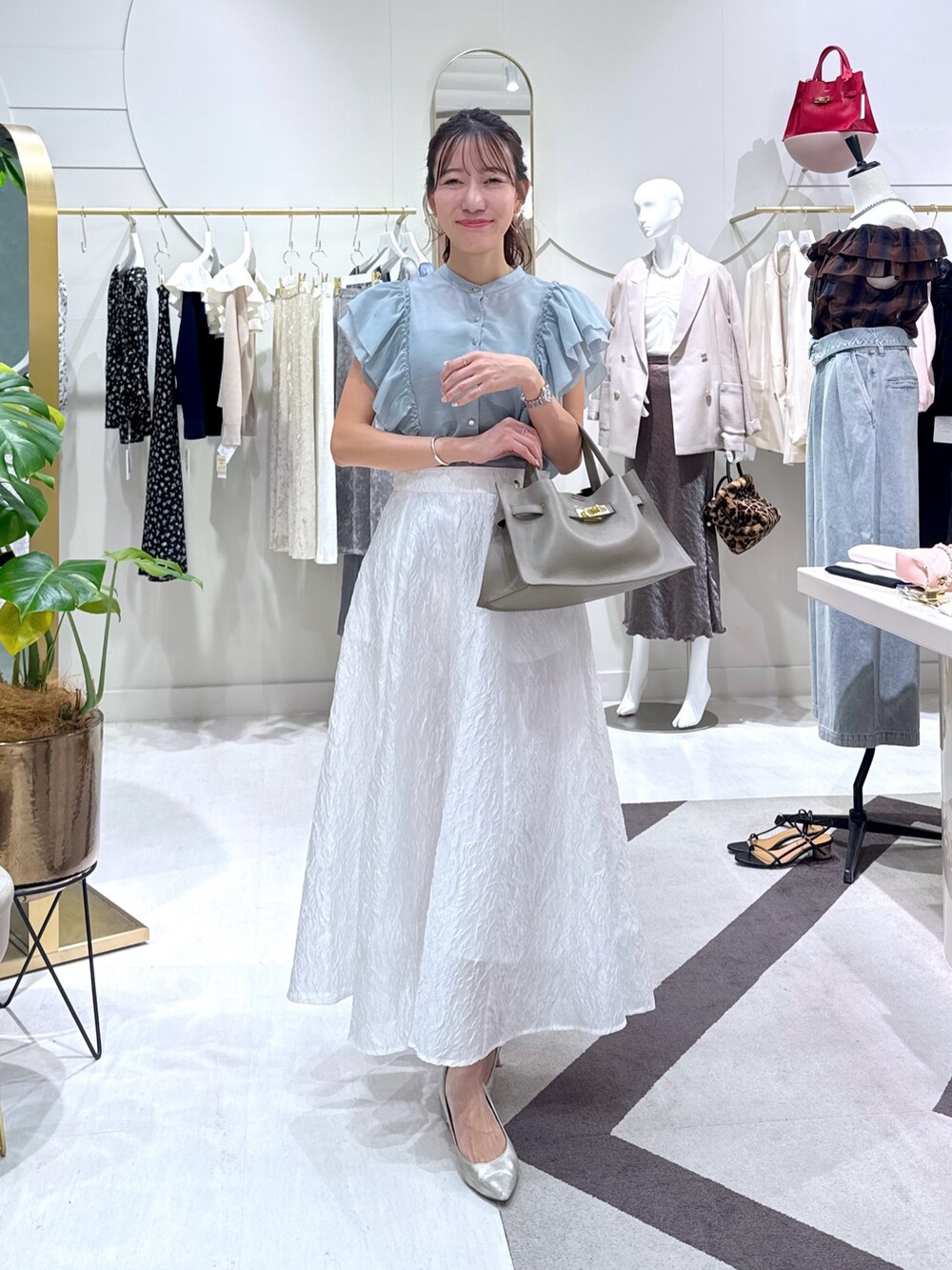 グレー系のトートバッグ、グリーン系のシャツ/ブラウス、ホワイト系のスカートを着用したレディースの秋コーディネートの2枚目の写真