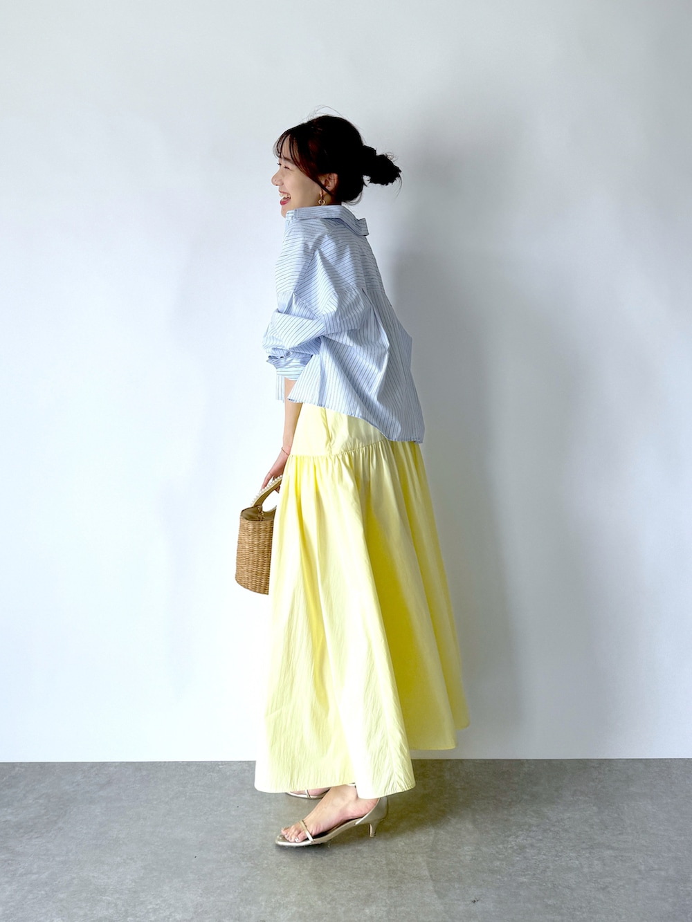 イエロー系のワンピース、ブルー系のシャツ/ブラウス、ホワイト系のタンクトップを着用したレディースの夏コーディネートの3枚目の写真