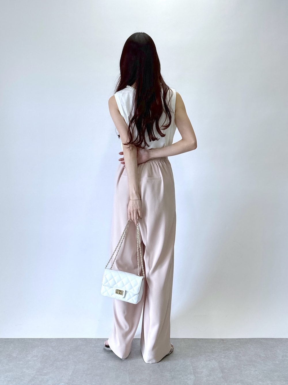 ピンク系のスラックス、ホワイト系のタンクトップを着用したレディースの春コーディネートの3枚目の写真