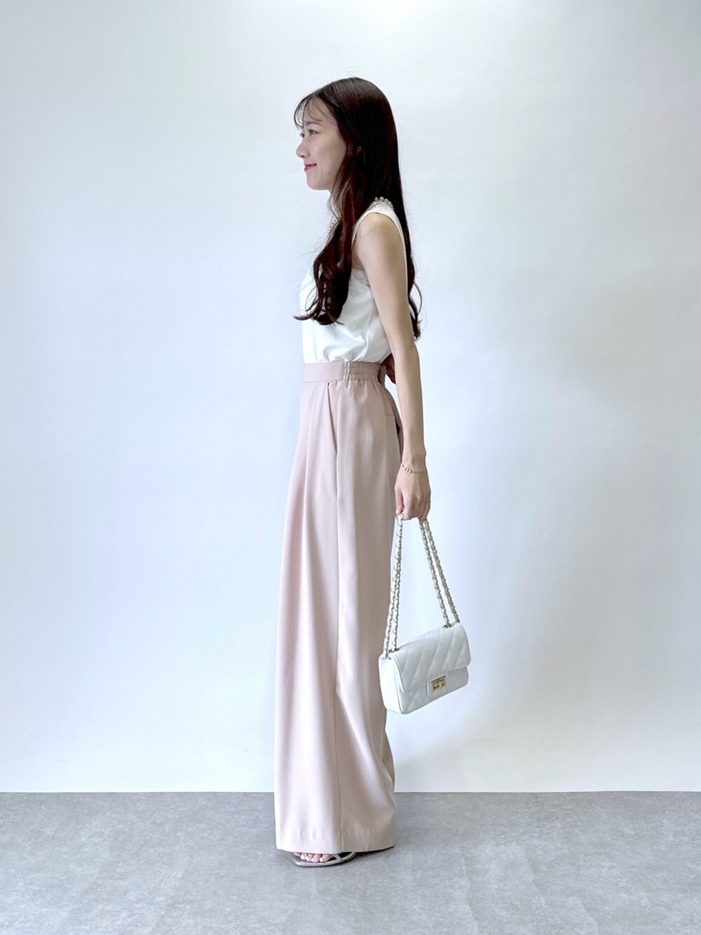 ピンク系のスラックス、ホワイト系のタンクトップを着用したレディースの春コーディネートの2枚目の写真