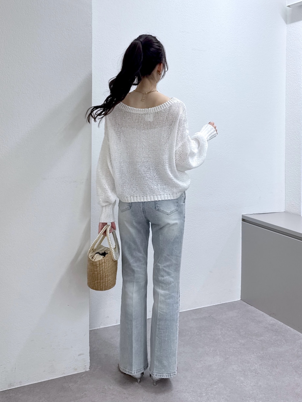 ホワイト系のニット/セーター、ブルー系のデニムパンツ、ベージュ系のかごバッグを着用したレディースの春コーディネートの4枚目の写真