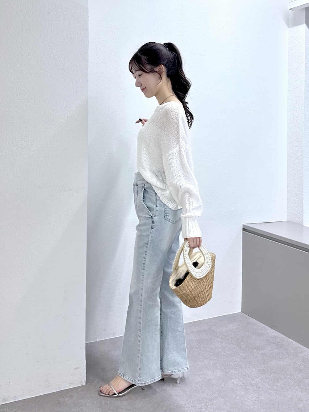 ホワイト系のニット/セーター、ブルー系のデニムパンツ、ベージュ系のかごバッグを着用したレディースの春コーディネートの3枚目の写真