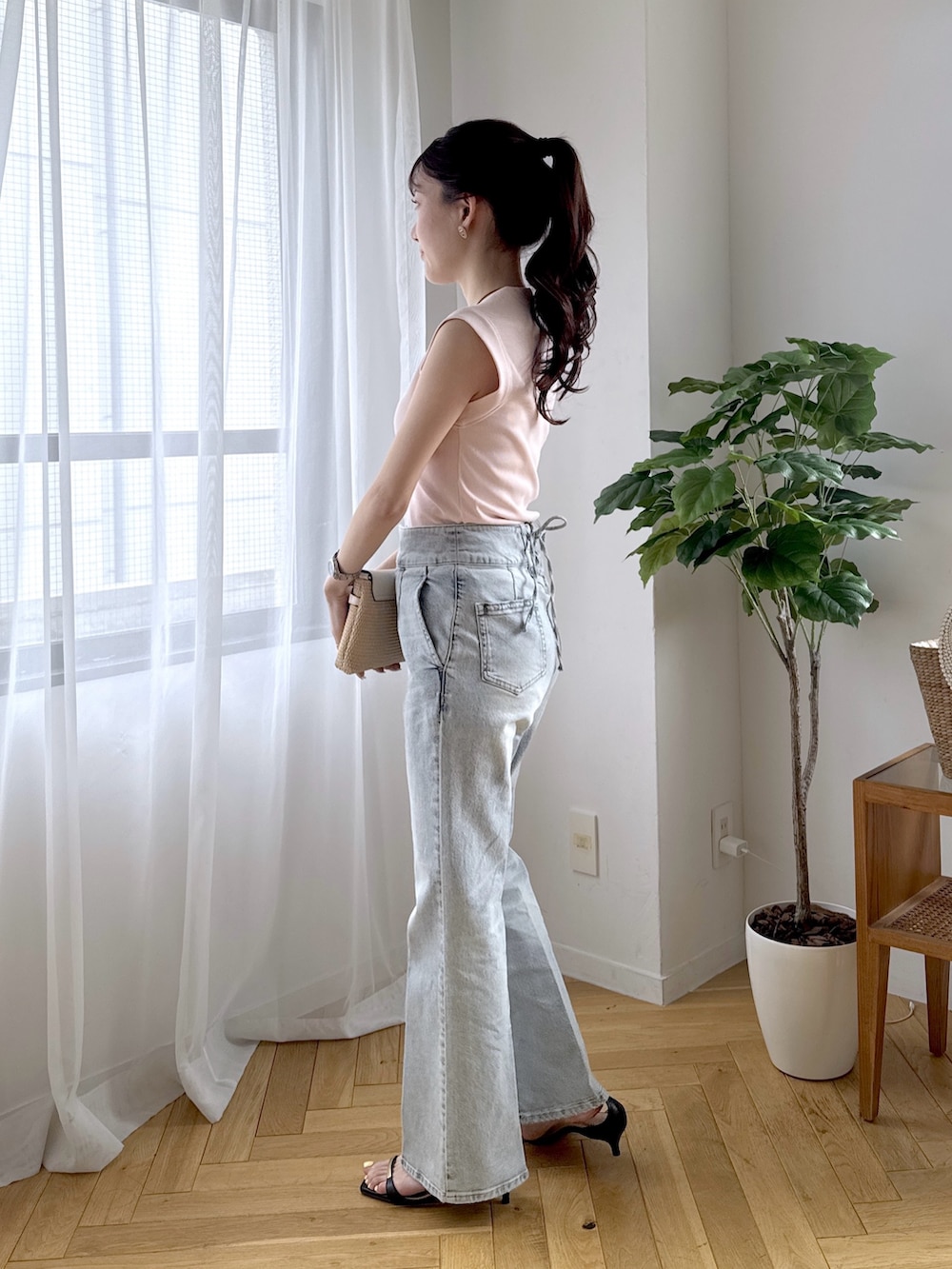 ピンク系のキャミソール、ブルー系のデニムパンツ、ブラック系のサンダルを着用したレディースの春コーディネートの2枚目の写真