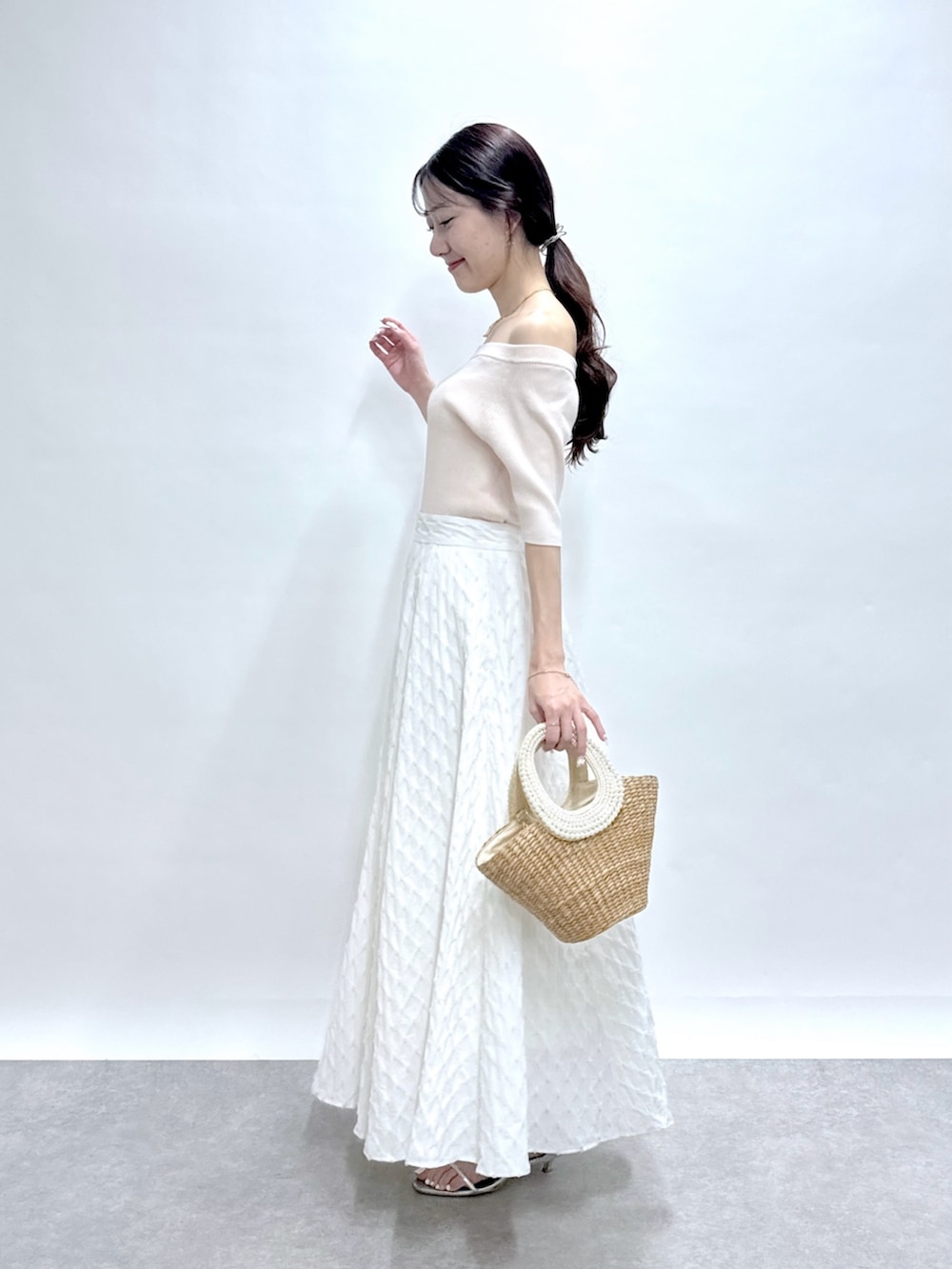 ピンク系のニット/セーター、ホワイト系のスカート、ベージュ系のかごバッグを着用したレディースの春コーディネートの3枚目の写真