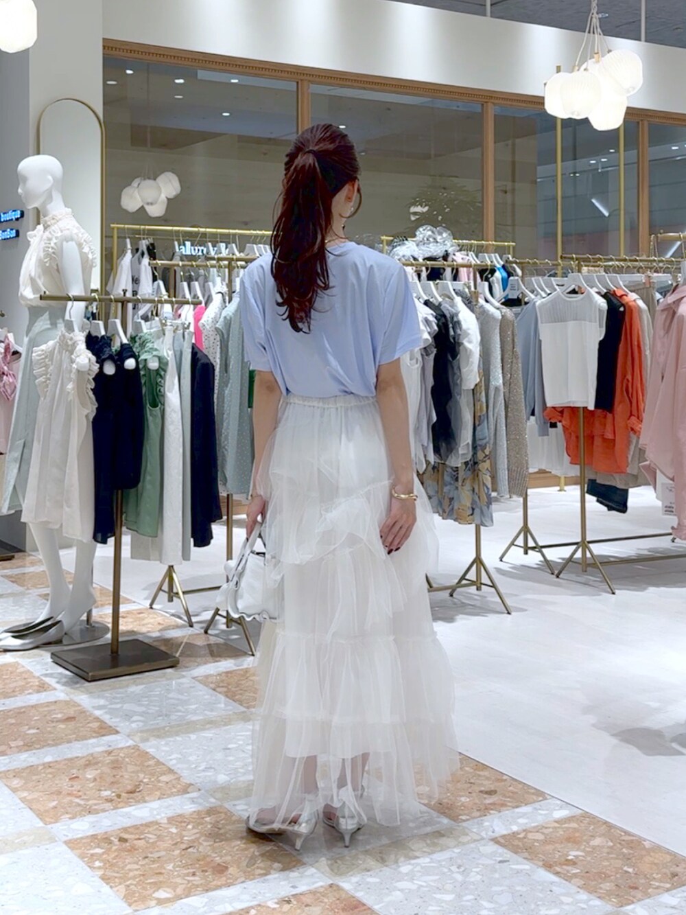 ホワイト系のトートバッグ、ホワイト系のスカート、ブルー系のTシャツ/カットソーを着用したレディースの夏コーディネートの3枚目の写真