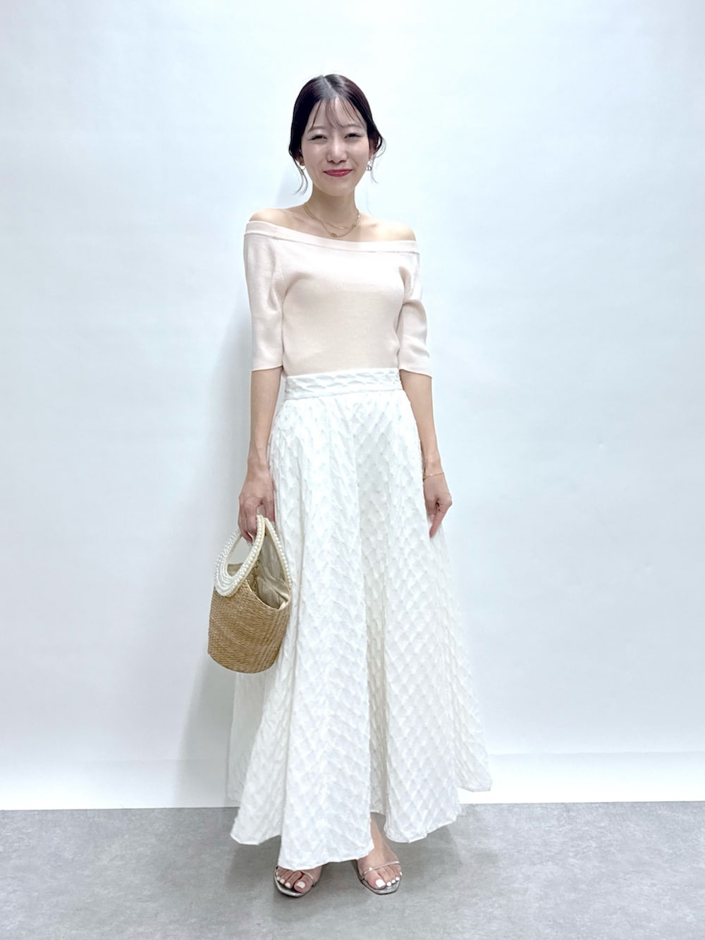 ピンク系のニット/セーター、ホワイト系のスカート、ベージュ系のかごバッグを着用したレディースの春コーディネートの2枚目の写真