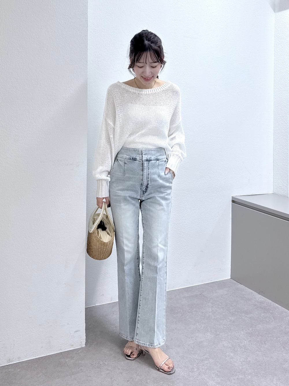 ホワイト系のニット/セーター、ブルー系のデニムパンツ、ベージュ系のかごバッグを着用したレディースの春コーディネートの5枚目の写真