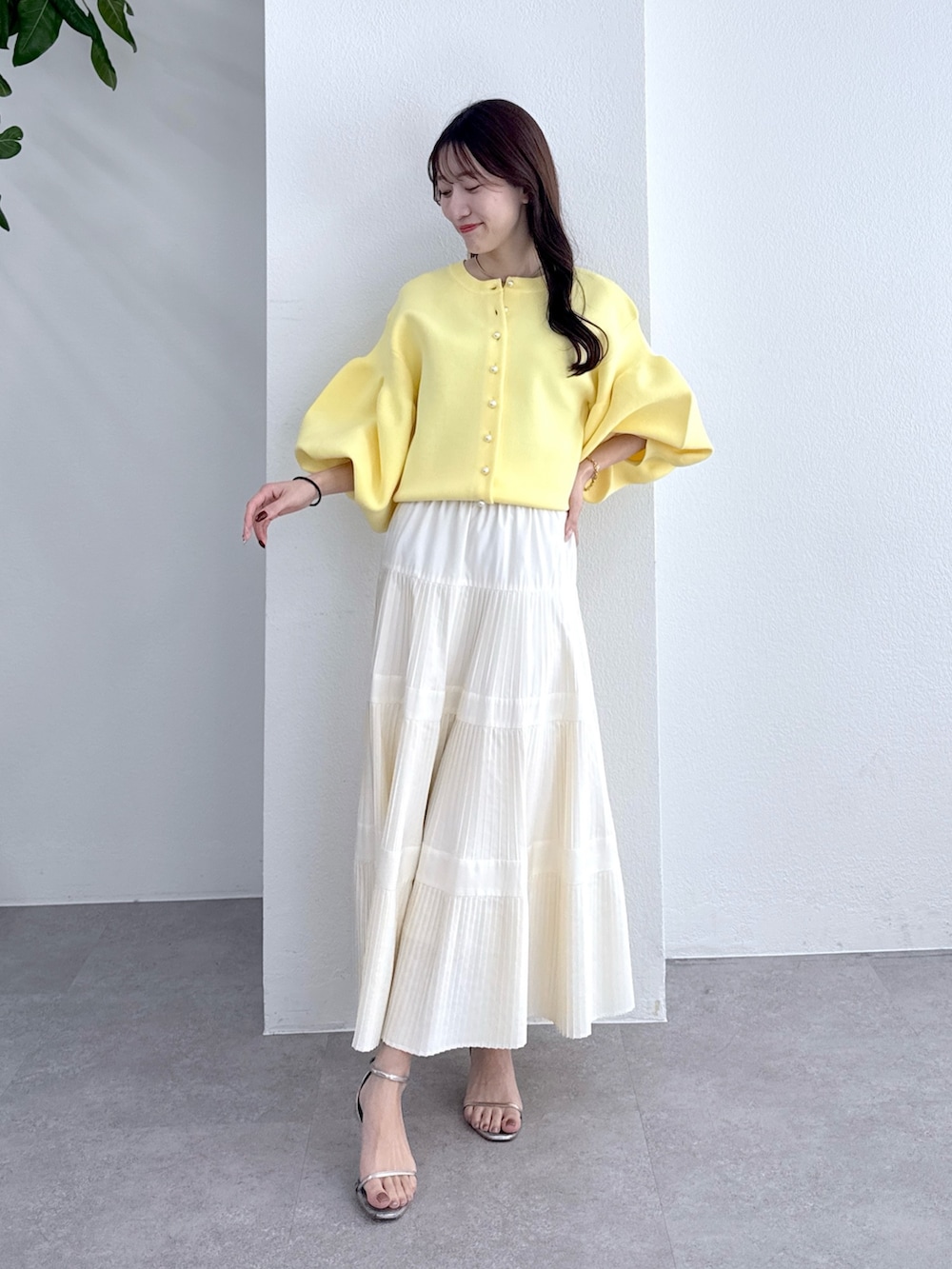 イエロー系のカーディガン/ボレロ、ホワイト系のスカートを着用したレディースの冬コーディネートの2枚目の写真