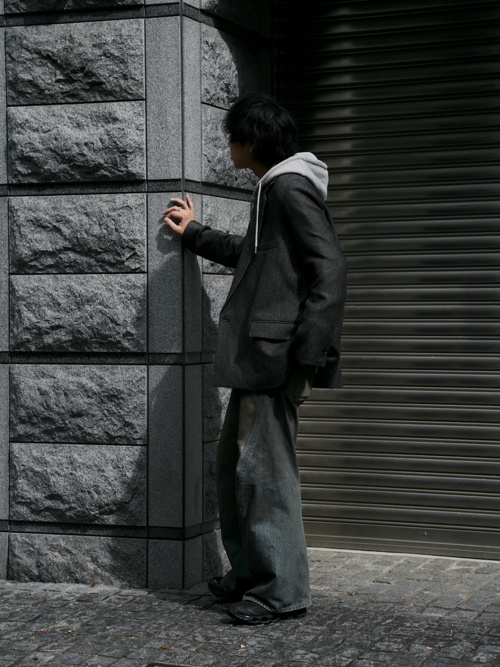 ブラウン系のテーラードジャケット、グレー系のパーカー、ブルー系のデニムパンツを着用したメンズの秋コーディネートの2枚目の写真