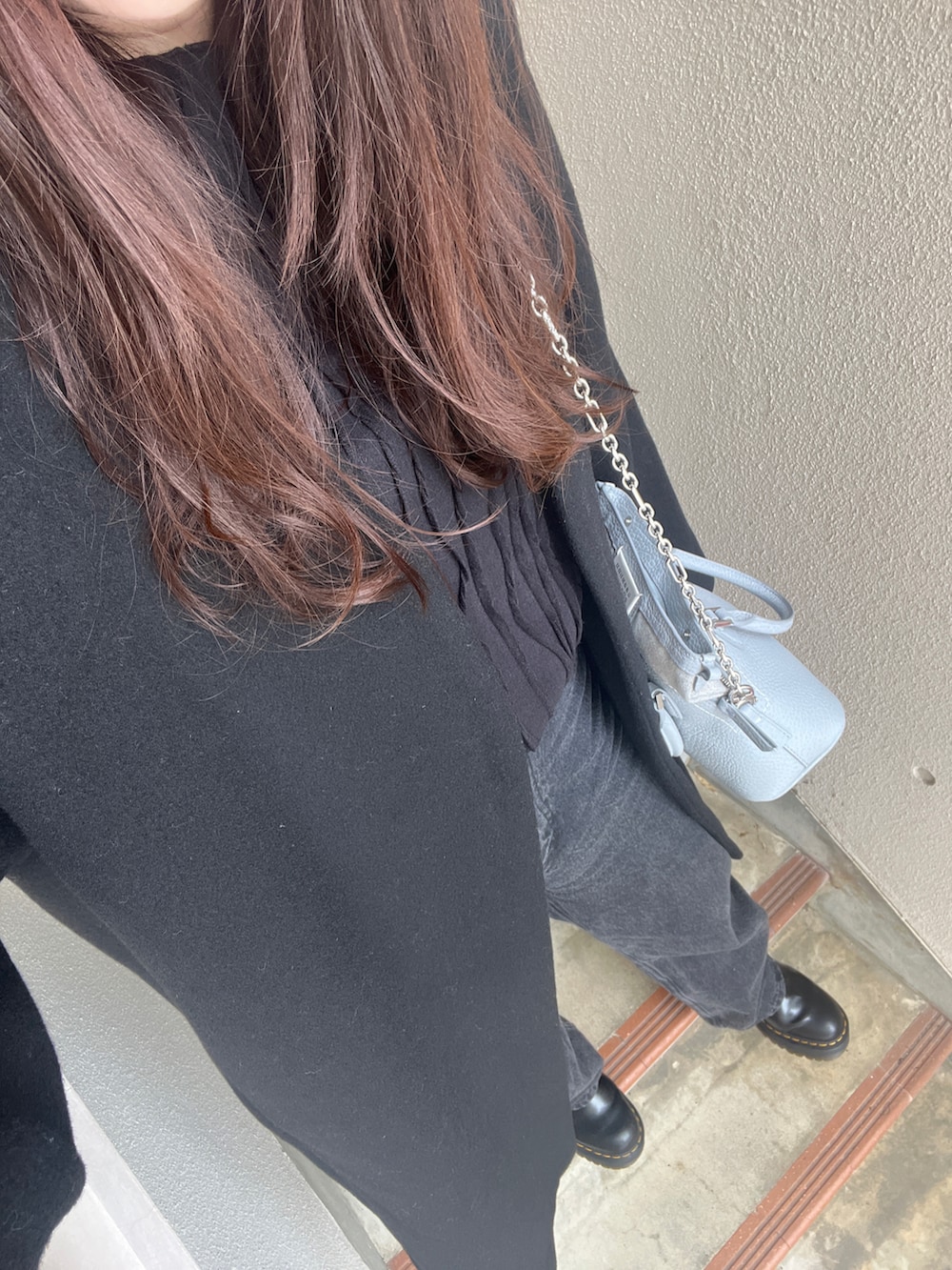 ブラック系のノーカラーコート、ブラック系のブーツ、ブルー系のバッグを着用したレディースの冬コーディネートの2枚目の写真