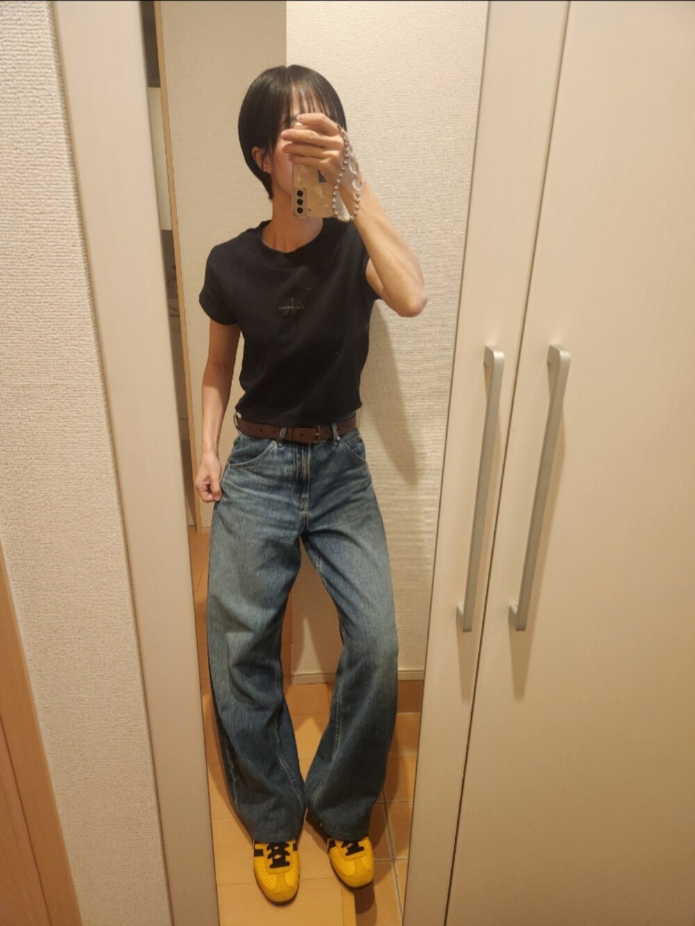 ブラック系のTシャツ/カットソー、ブルー系のデニムパンツ、イエロー系のスニーカーを着用したレディースの秋コーディネートの2枚目の写真