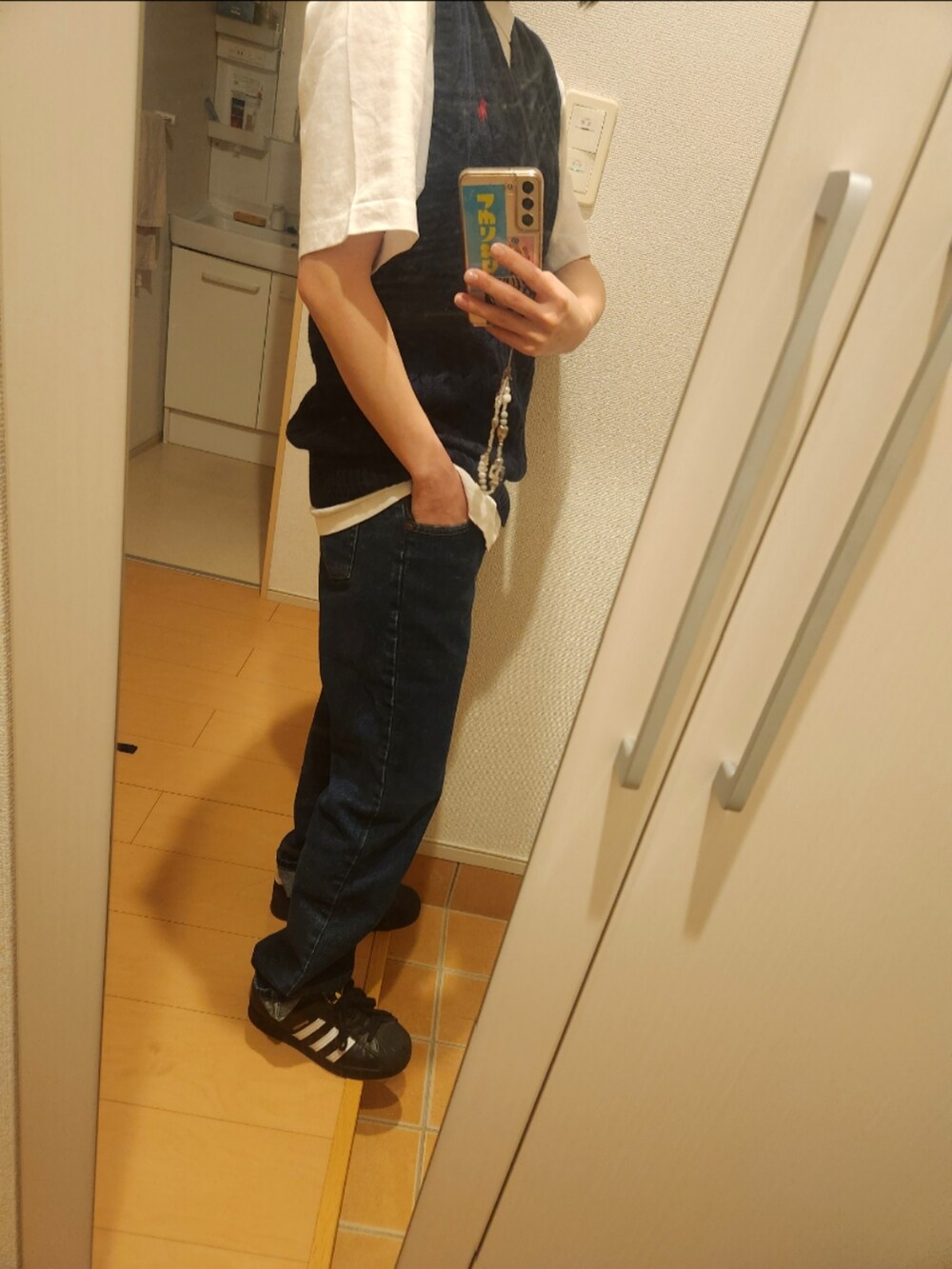 ブルー系のベスト、ホワイト系のシャツ/ブラウス、ブルー系のデニムパンツを着用したレディースの春コーディネートの2枚目の写真