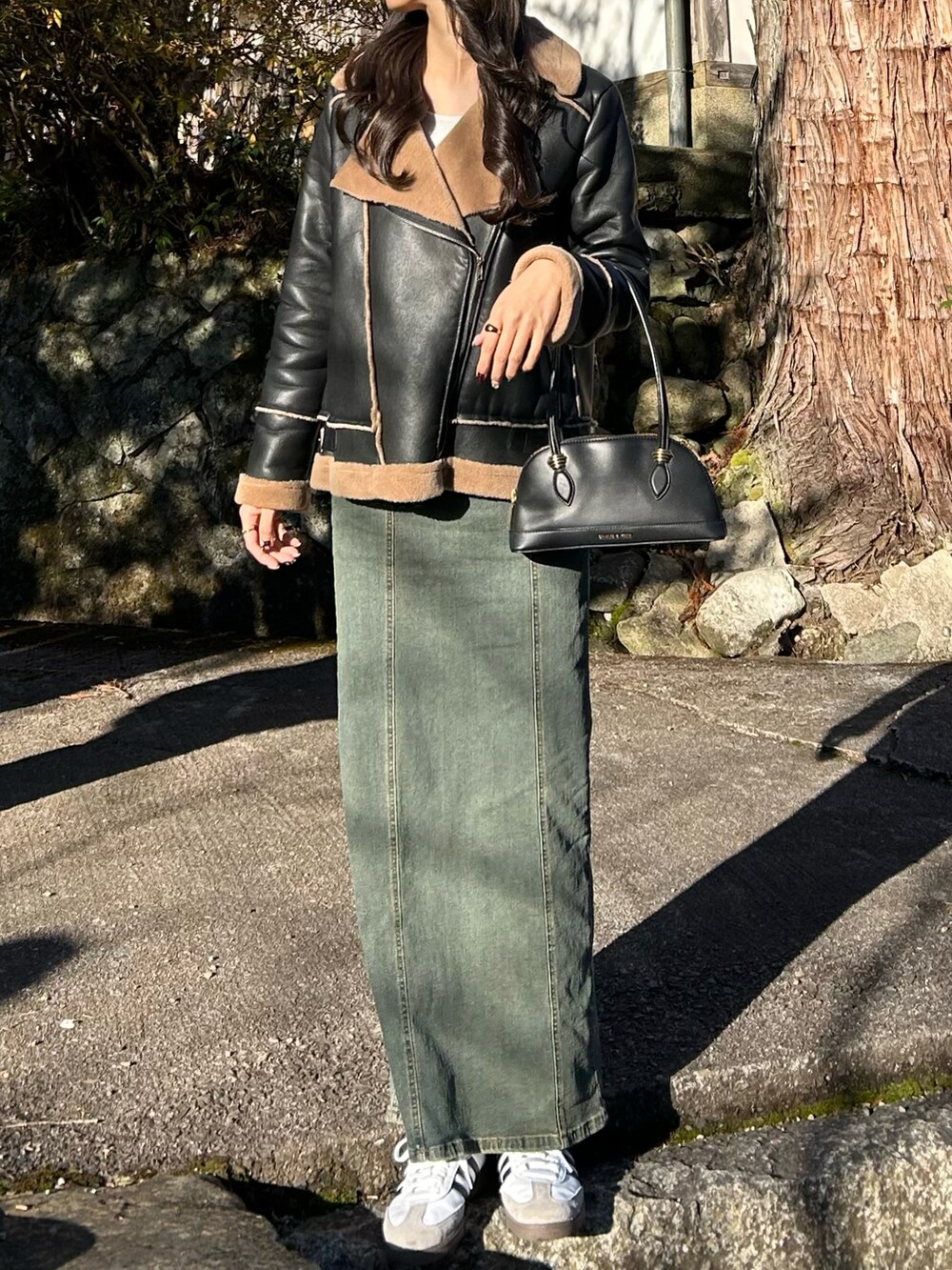 ブラック系のジャケット/アウター、ブルー系のワンピース、ホワイト系のスニーカーを着用したレディースの冬コーディネートの2枚目の写真