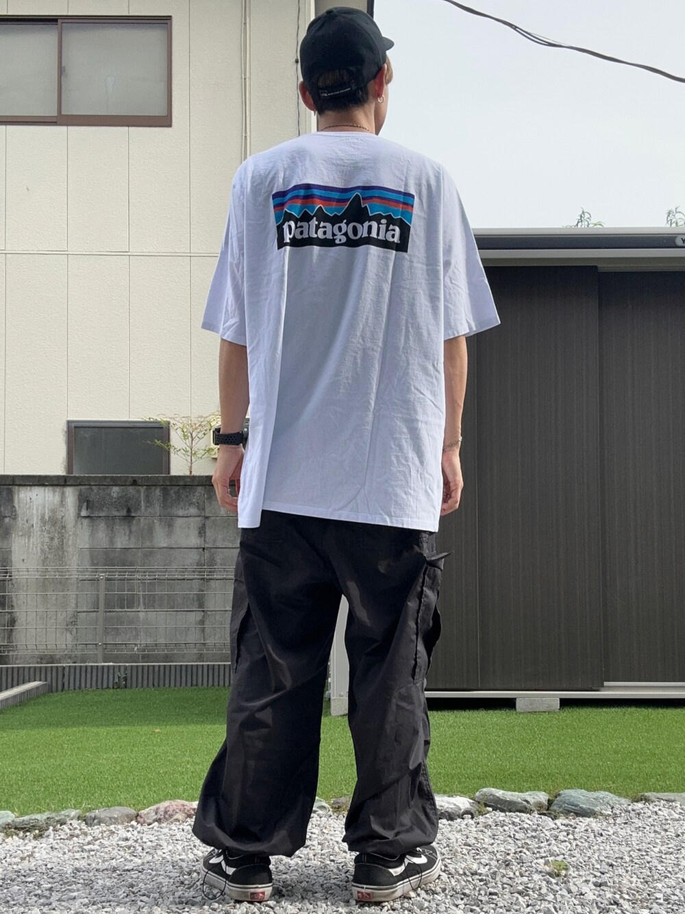 ホワイト系のTシャツ/カットソー、ブラック系のカーゴパンツ、ブラック系のスニーカーを着用したメンズの夏コーディネートの2枚目の写真