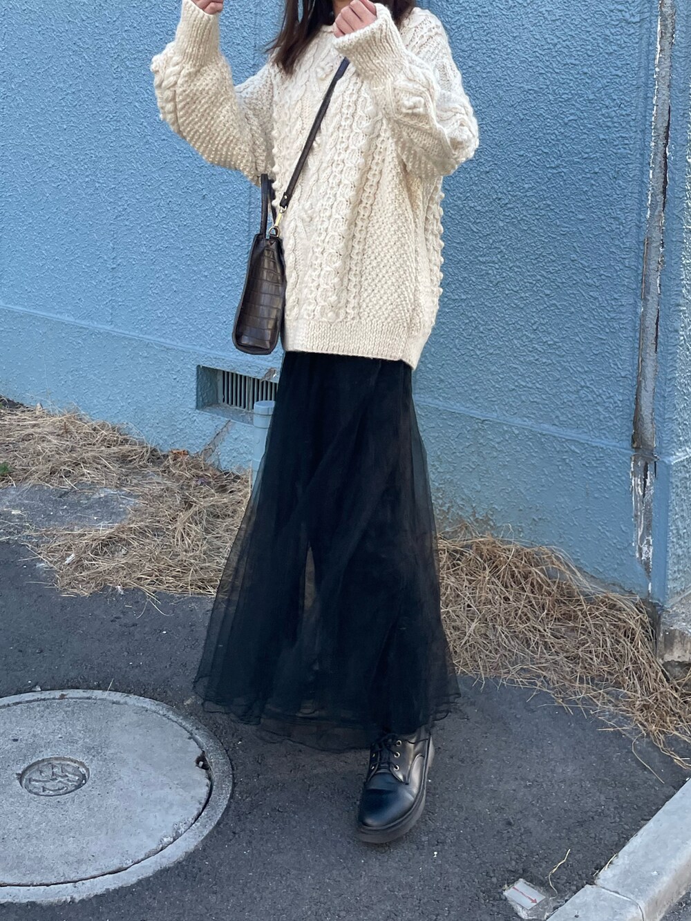 ホワイト系のニット/セーター、ブラック系のスカートを着用したレディースの冬コーディネートの2枚目の写真