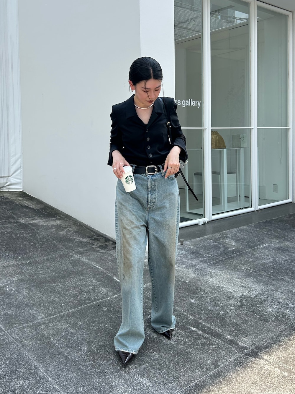 ブラック系のパンプス、ブルー系のデニムパンツ、ブラック系のベルトを着用したレディースの冬コーディネートの2枚目の写真