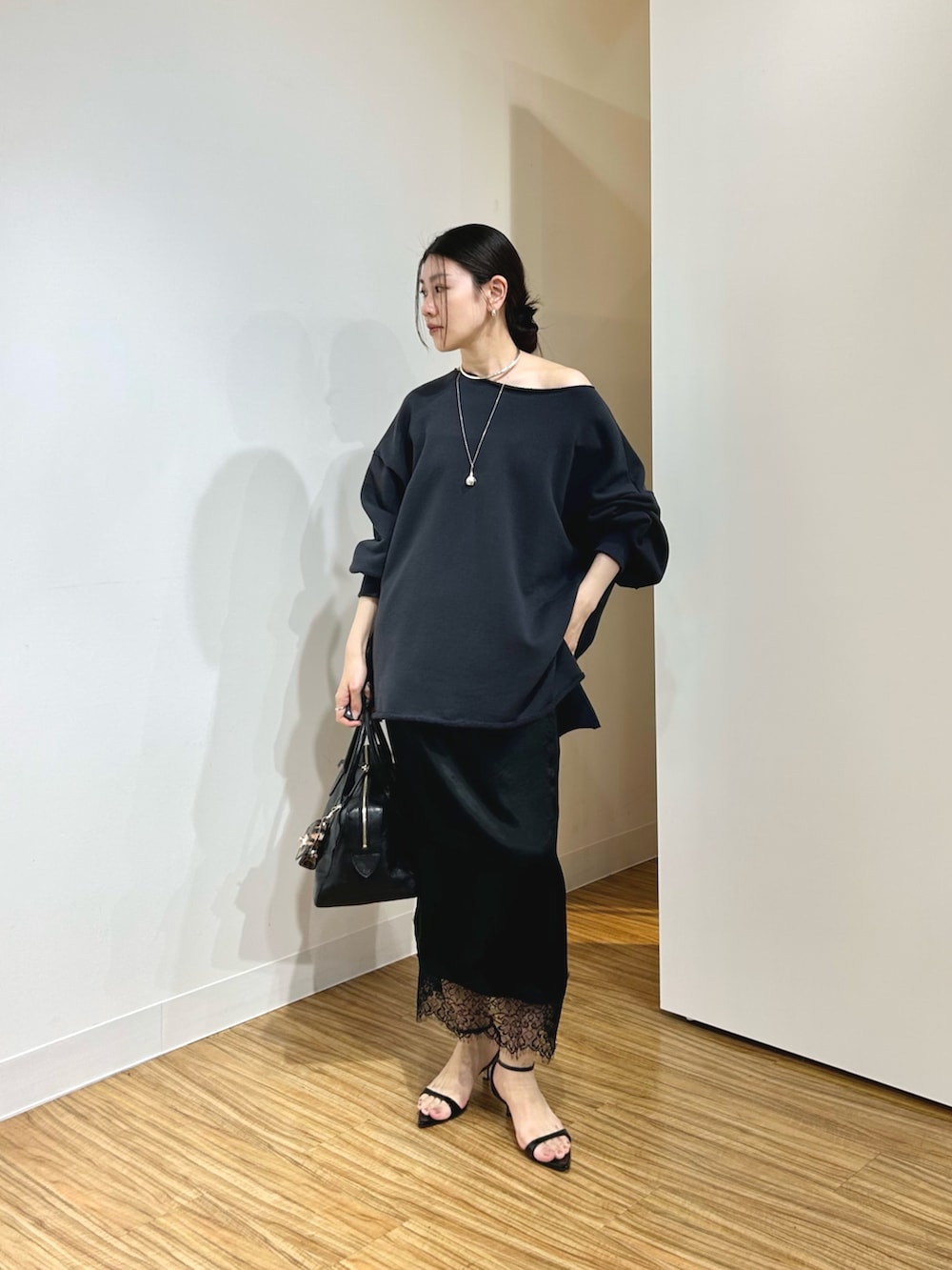 グレー系のスウェット、ブラック系のサンダル、ブラック系のスカートを着用したレディースの春コーディネートの2枚目の写真