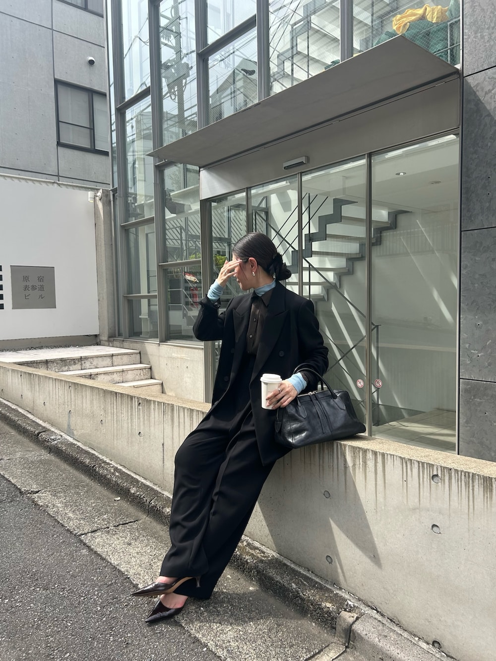 ブラック系のテーラードジャケット、ブラック系のトートバッグ、ブラウン系のパンプスを着用したレディースの秋コーディネートの2枚目の写真