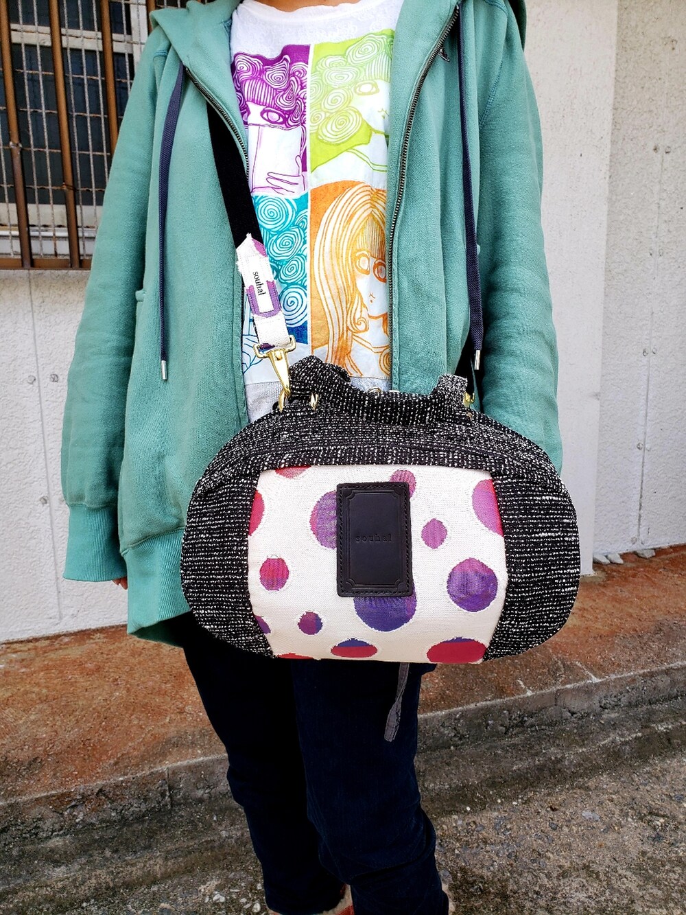 グリーン系のブルゾン、ホワイト系のTシャツ/カットソー、ブラック系のショルダーバッグを着用したレディースの春コーディネートの3枚目の写真