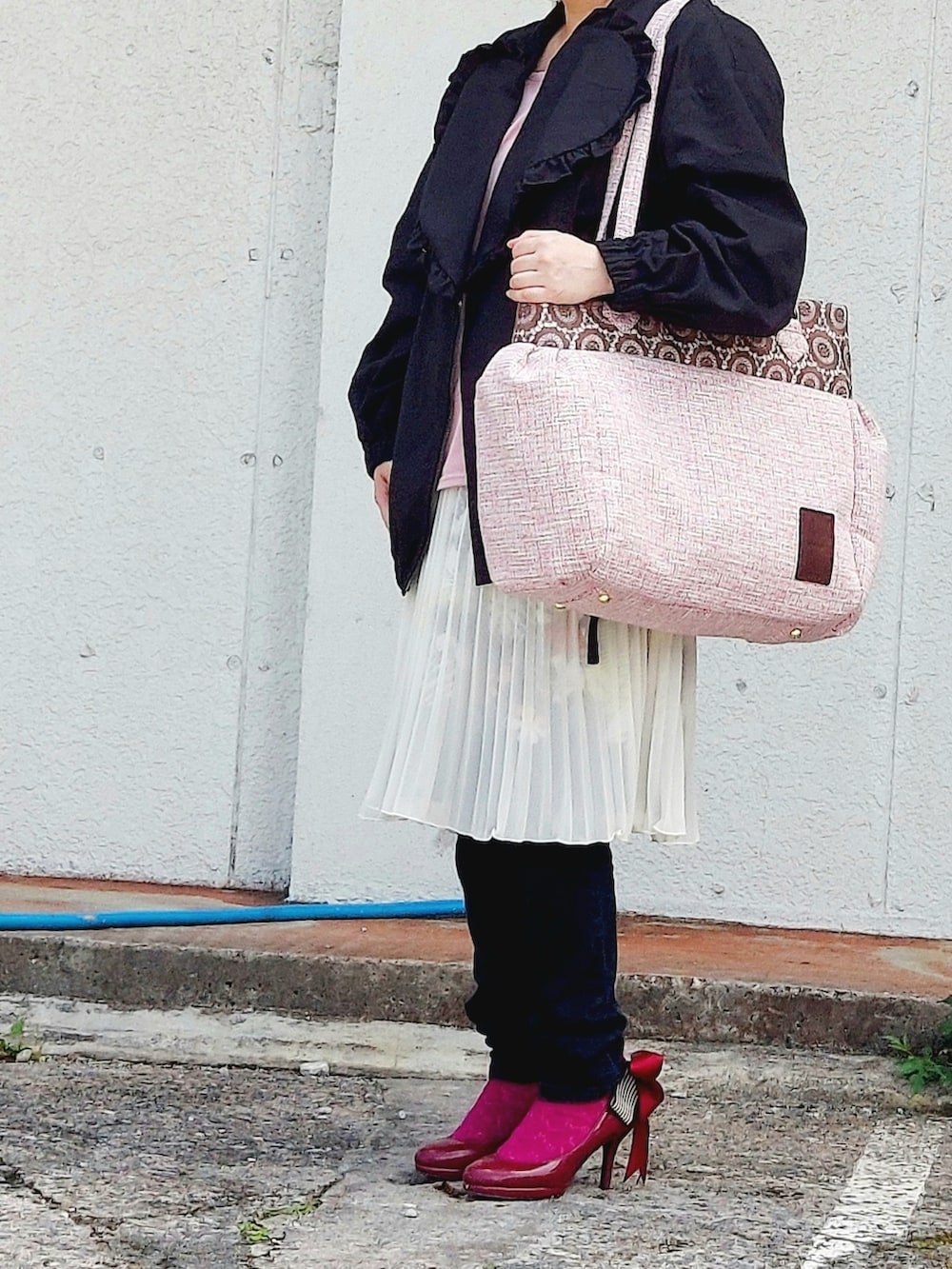 ブラック系のブルゾン、ピンク系のショルダーバッグ、ホワイト系のスカートを着用したレディースの春コーディネートの2枚目の写真