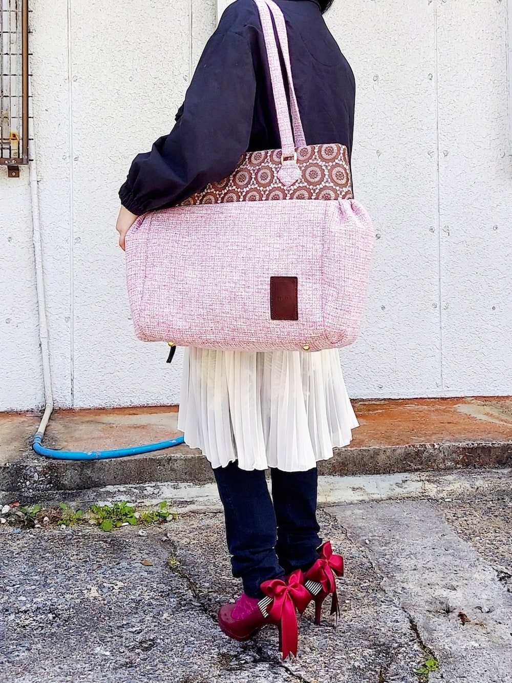 ブラック系のブルゾン、ピンク系のショルダーバッグ、ホワイト系のスカートを着用したレディースの春コーディネートの3枚目の写真