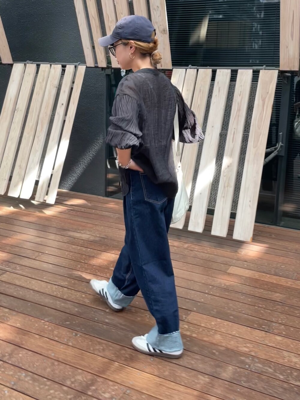 ブラック系のシャツ/ブラウス、ブルー系のデニムパンツ、ホワイト系のスニーカーを着用したレディースの秋コーディネートの4枚目の写真