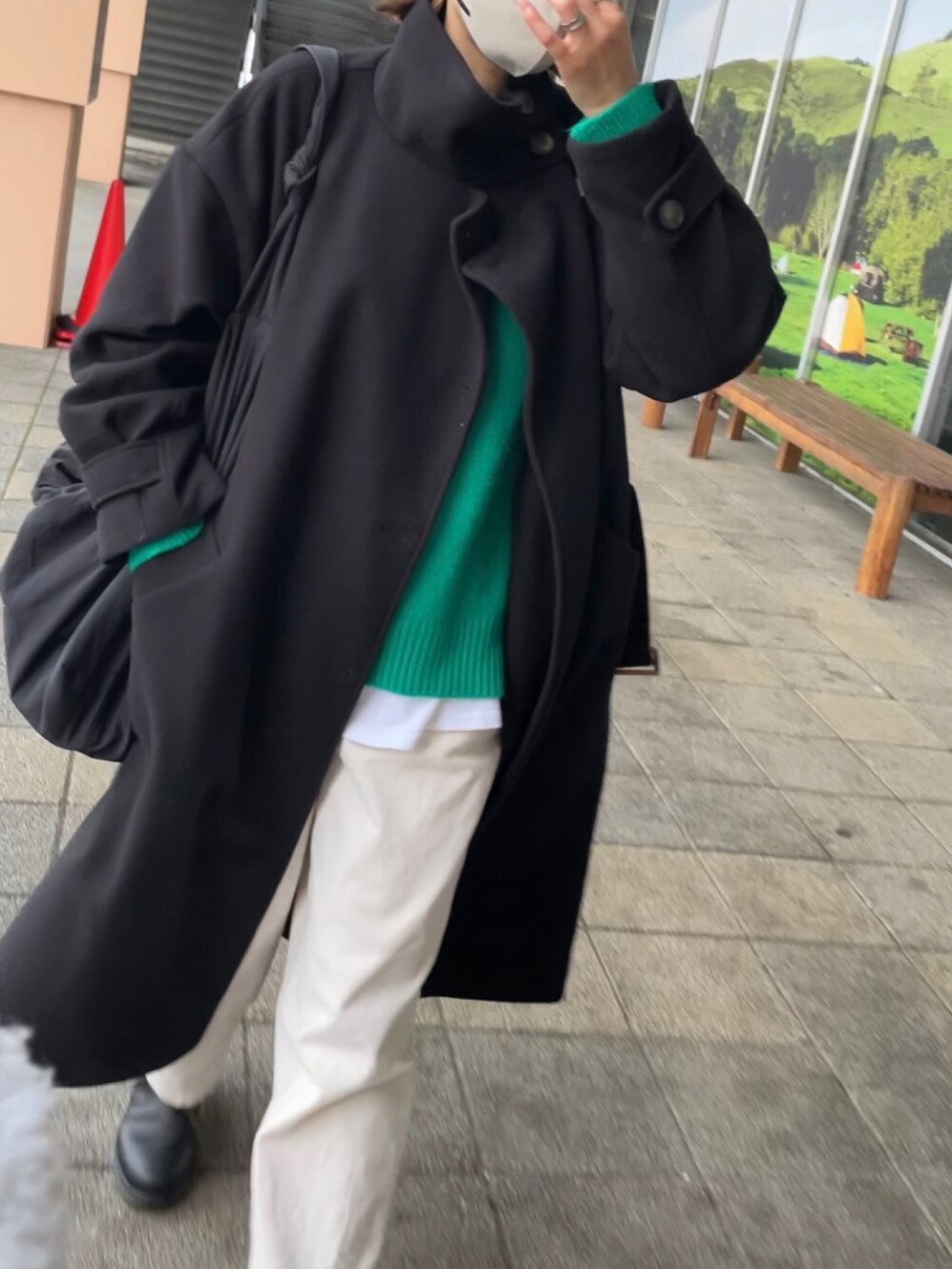 ブラック系のトレンチコート、グリーン系のニット/セーター、ホワイト系のパンツを着用したレディースの冬コーディネートの4枚目の写真