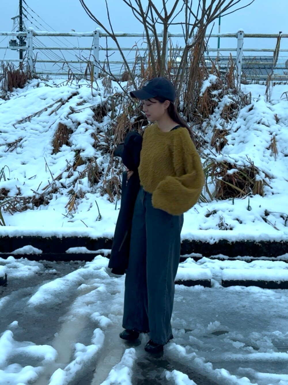 グリーン系のニット/セーター、ブラック系のデニムパンツ、ブラック系のブーツを着用したレディースの冬コーディネートの3枚目の写真