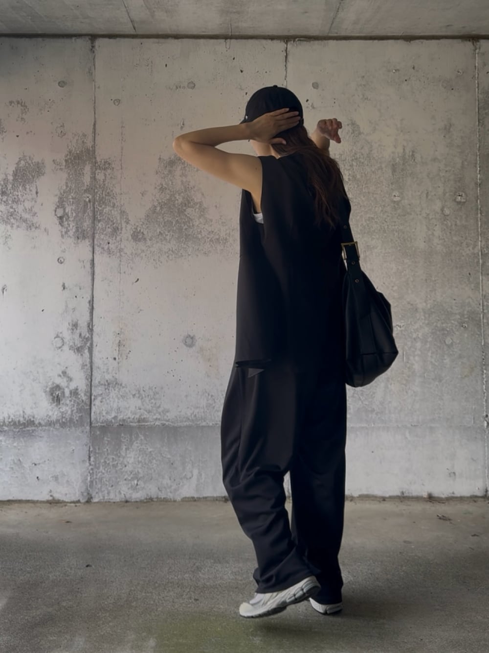 ブラック系のベスト、ブラック系のスラックス、グレー系のスニーカーを着用したレディースの秋コーディネートの4枚目の写真