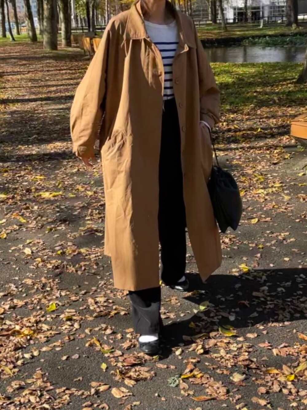 ベージュ系のステンカラーコート、その他のTシャツ/カットソー、ブラック系のパンツを着用したレディースの秋コーディネートの3枚目の写真