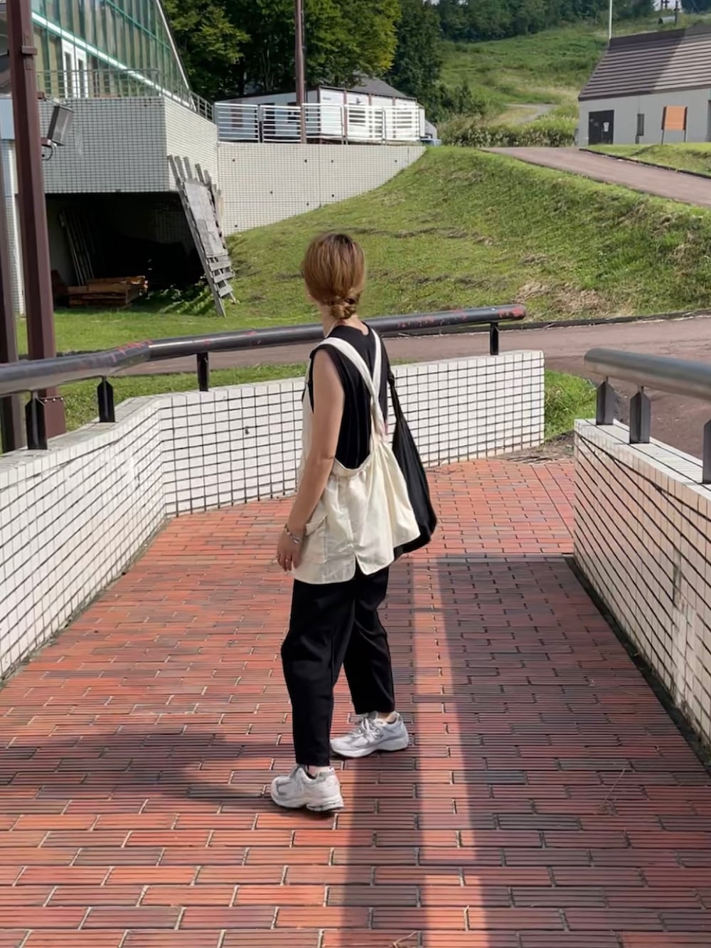 ベージュ系のベスト、ブラック系のその他パンツ、グレー系のスニーカーを着用したレディースの秋コーディネートの2枚目の写真