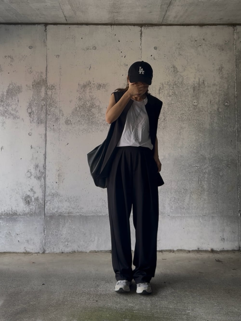 ブラック系のベスト、ブラック系のスラックス、グレー系のスニーカーを着用したレディースの秋コーディネートの3枚目の写真