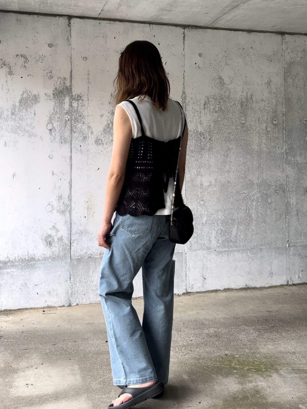 ブラック系のニット/セーター、ブラック系のショルダーバッグ、ブルー系のデニムパンツを着用したレディースの夏コーディネートの3枚目の写真