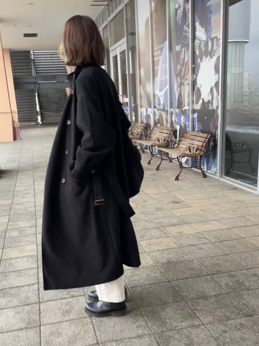 ブラック系のトレンチコート、グリーン系のニット/セーター、ホワイト系のパンツを着用したレディースの冬コーディネートの3枚目の写真