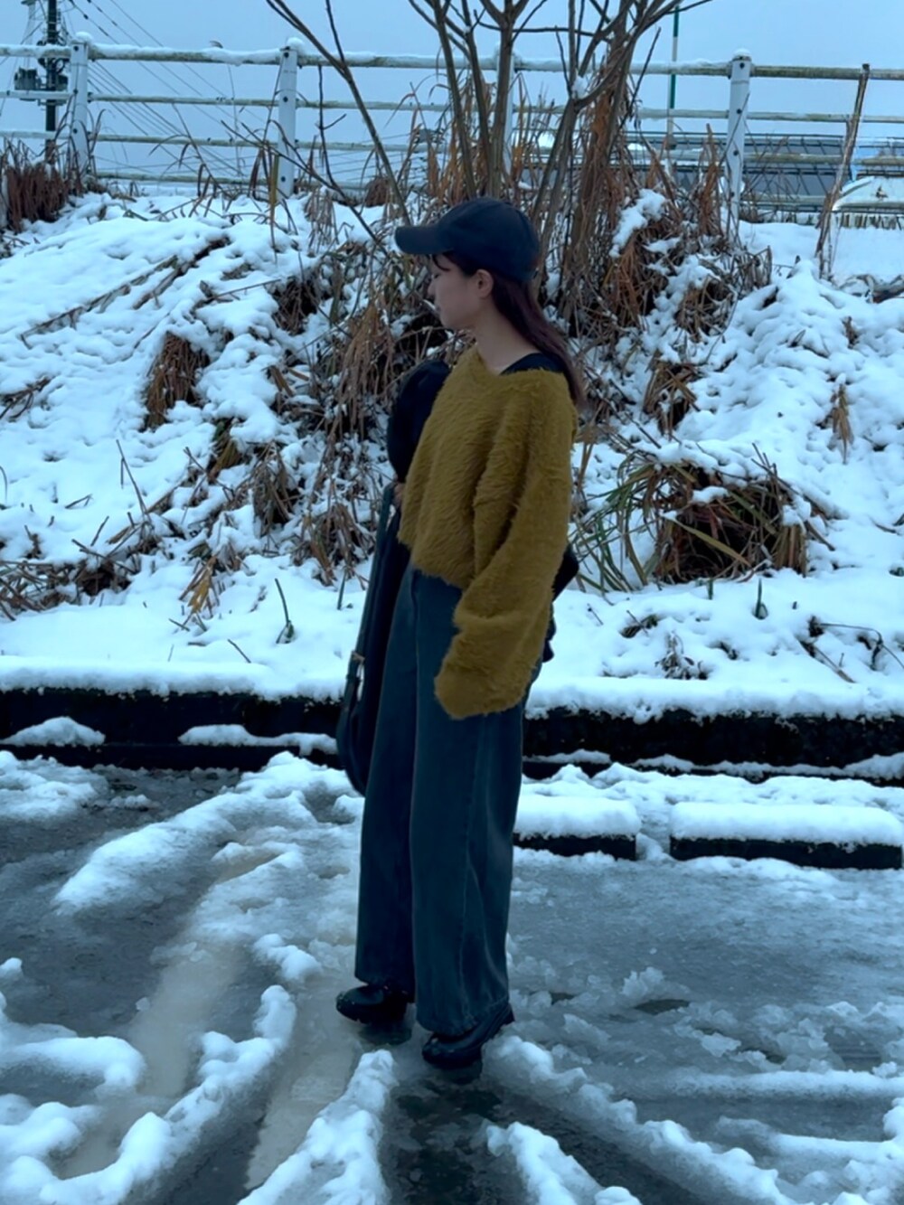 グリーン系のニット/セーター、ブラック系のデニムパンツ、ブラック系のブーツを着用したレディースの冬コーディネートの2枚目の写真