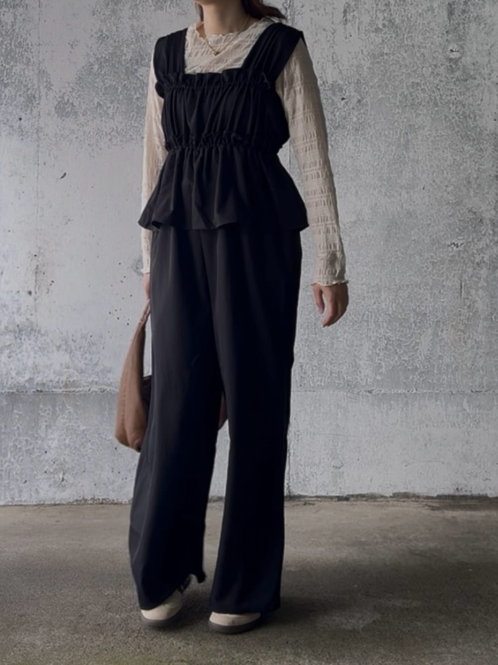 ベージュ系のTシャツ/カットソー、ブラック系のサロペット/オーバーオール、ベージュ系のスニーカーを着用したレディースの冬コーディネートの3枚目の写真