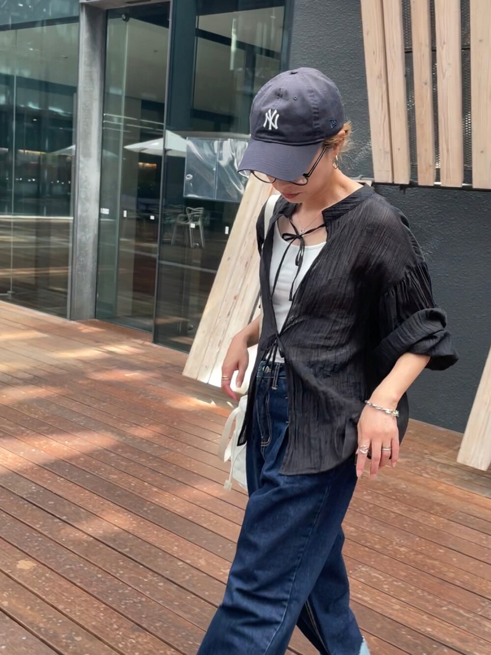 ブラック系のシャツ/ブラウス、ブルー系のデニムパンツ、ホワイト系のスニーカーを着用したレディースの秋コーディネートの2枚目の写真