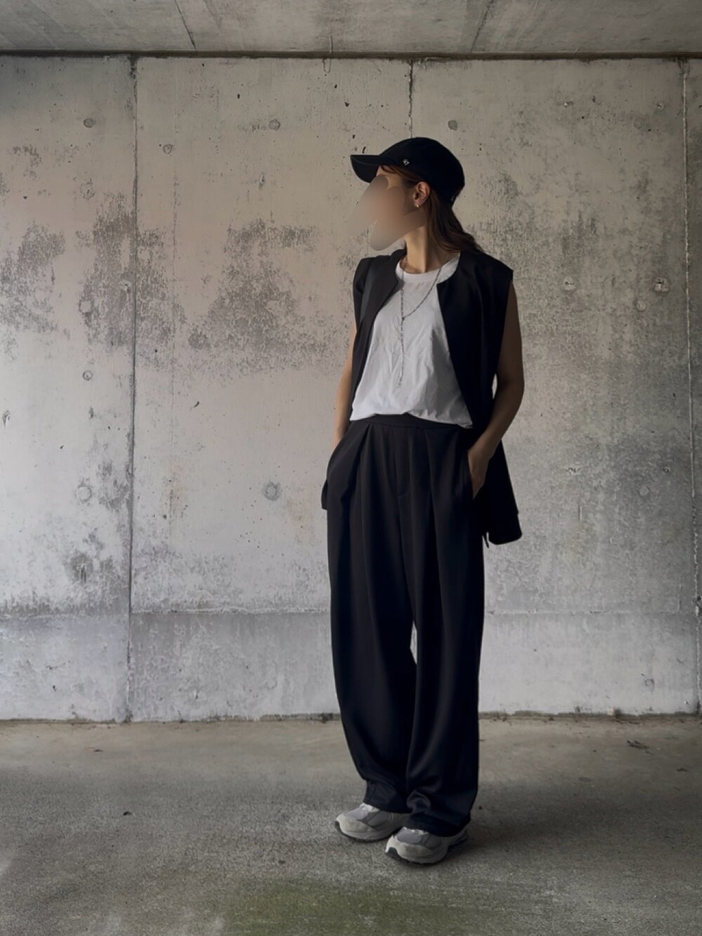 ブラック系のベスト、ブラック系のスラックス、グレー系のスニーカーを着用したレディースの秋コーディネートの2枚目の写真