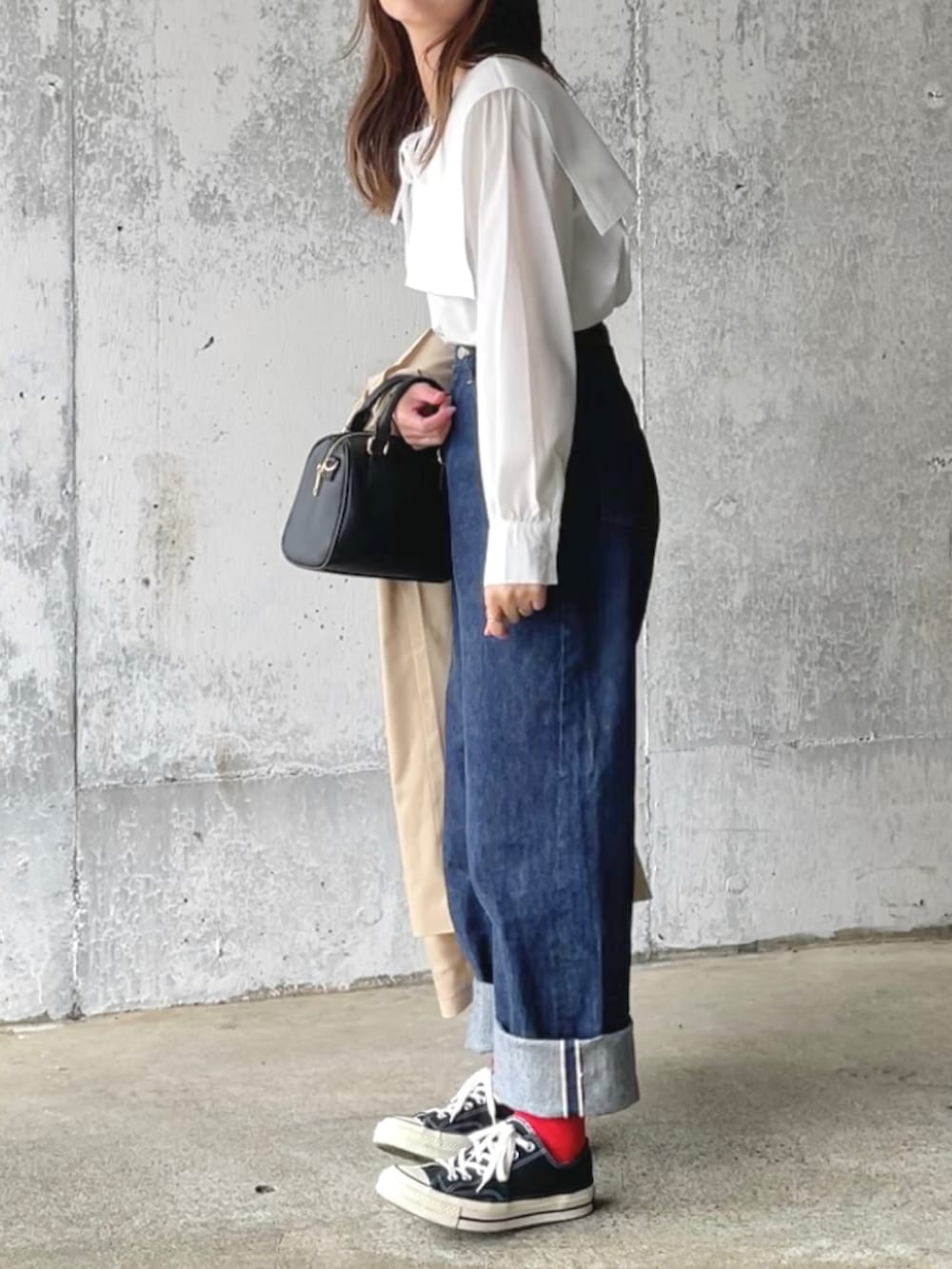 ブルー系のデニムパンツ、ブラック系のハンドバッグ、ブラック系のスニーカーを着用したレディースの春コーディネートの2枚目の写真