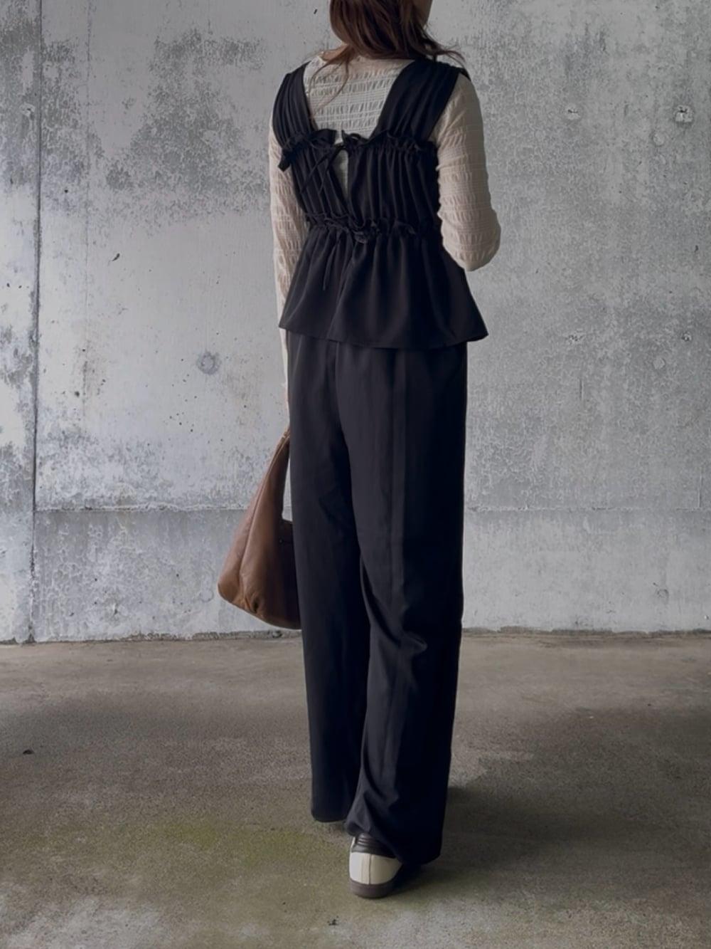 ベージュ系のTシャツ/カットソー、ブラック系のサロペット/オーバーオール、ベージュ系のスニーカーを着用したレディースの冬コーディネートの2枚目の写真