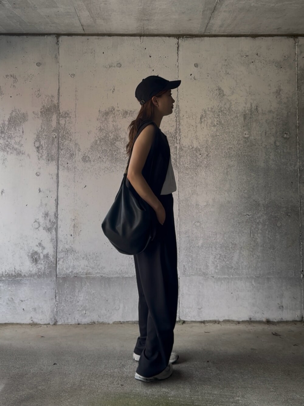 ブラック系のベスト、ブラック系のスラックス、グレー系のスニーカーを着用したレディースの秋コーディネートの5枚目の写真